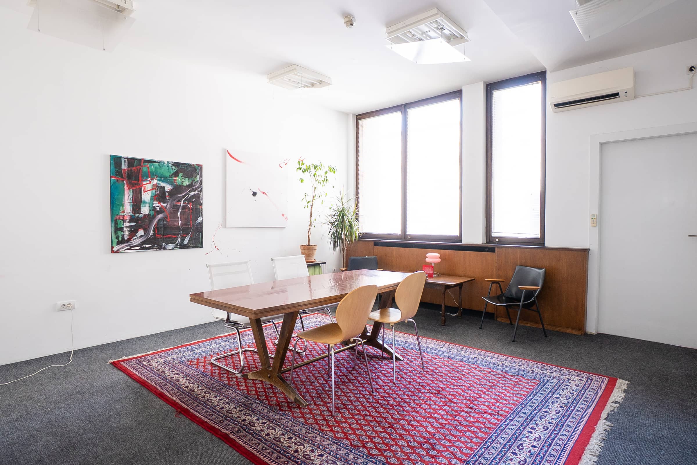 Conference table at SENSE—S.SPACE with mid-century chairs on a patterned rug